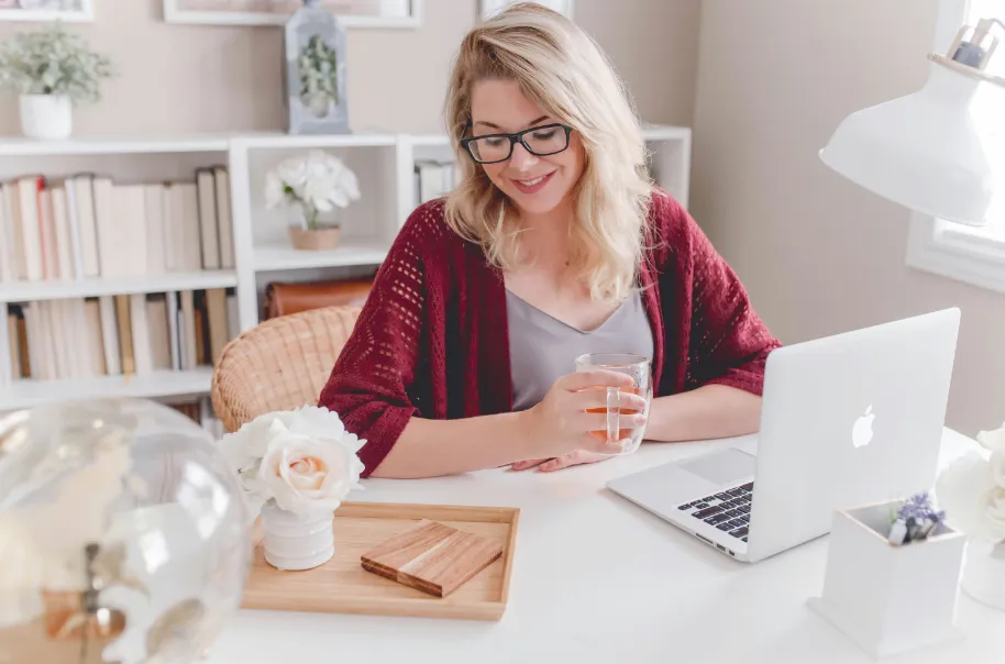 A blonde woman in her home using her laptop